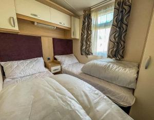 a bedroom with two beds in a small room at Lovely Caravan With Spacious Decking At North Denes In Suffolk, Ref 40134nd in Lowestoft