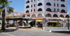 a large white building with a palm tree in front of it at Estudio en Tenerife sur, Parque Santiago 2 in Arona