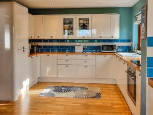 Ceardach في Gelston: مطبخ به دواليب بيضاء وبلاط ازرق
