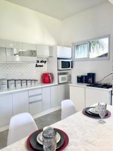 cocina blanca con mesa y armarios blancos en Santinho Ocean View House, en Florianópolis