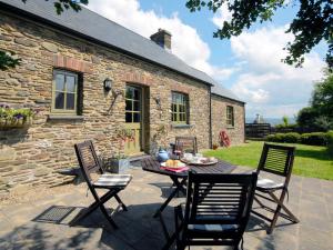 a table and chairs in front of a stone house at Yr Hen Gof in Mathry
