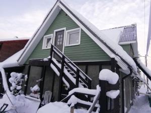 uma casa verde com neve nas escadas em Lili stuudio em Otepää