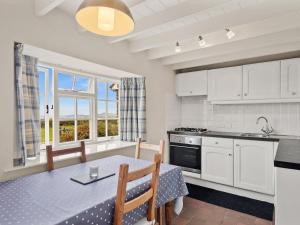 a kitchen and dining room with a table and chairs and a window at Ty Gwartheg in Trevine