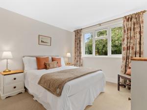 a white bedroom with a bed and a window at Ty Gwartheg in Trevine