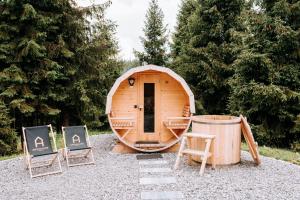 a small wooden cabin with chairs and a barrel at ArtHouse Podhale in Klikuszowa +12 photos