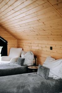 two beds in a room with wooden walls at ArtHouse Podhale in Klikuszowa