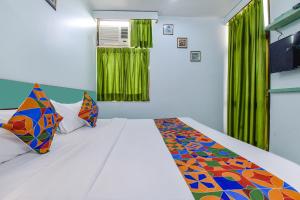 een slaapkamer met een wit bed en kleurrijke kussens bij FabHotel Aayojan in Jaipur