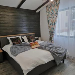 een slaapkamer met een groot bed en een houten muur bij Chalet Amik in Buşteni