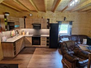 ein Wohnzimmer mit einem Ledersofa und einer Küche in der Unterkunft Chaty u lesa in Velké Hamry