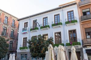 un edificio blanco con sombrillas delante en BiBo Suites San Agustín en Granada