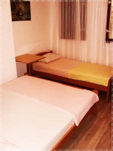 two beds in a small room with wooden floors at Guest House Oleander in Petrovac na Moru