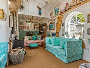 uma sala de estar com mobiliário azul e uma janela arqueada em Willow Cottage em St Just