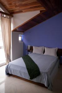 1 dormitorio con 1 cama grande y pared azul en Bela Sombra en Vila da Ribeira Brava