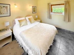 1 dormitorio con cama blanca y ventana en Blossoms Cottage, en Albourne