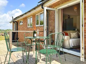 a patio with a table and chairs and a bedroom at Blossoms Cottage in Albourne