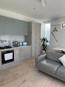 ein Wohnzimmer mit einem Sofa und einer Küche in der Unterkunft Plateau Of The Seas in Collaroy