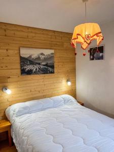 a bedroom with a white bed with a wooden wall at T1 Cosy Pleine station de ski in Bellevaux