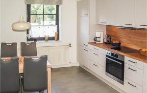 a kitchen with white cabinets and a table with chairs at Cozy Home In Burg Stargard With Wifi in Burg Stargard