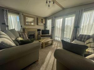 a living room with couches and a tv and windows at Lovely Caravan With Decking At Carlton Meres Holiday Park In Suffolk Ref 60023ch in Saxmundham
