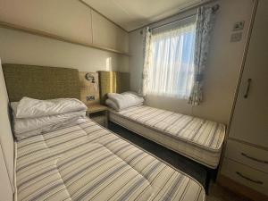 1 Schlafzimmer mit 2 Betten und einem Fenster in der Unterkunft Lovely Caravan With Decking At Carlton Meres Holiday Park In Suffolk Ref 60023ch in Saxmundham