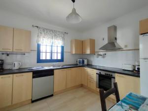 kuchnia z drewnianymi szafkami i oknem w obiekcie Villa Rubicón Costa w mieście Playa Blanca