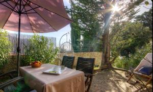 una mesa con sombrilla y 2 sillas con el sol en Gîtes et Astrotourisme en Corse, en Erbajolo