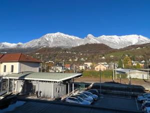 un groupe de voitures garées sur un parking avec des montagnes enneigées dans l'établissement Albert 1er, à Albertville