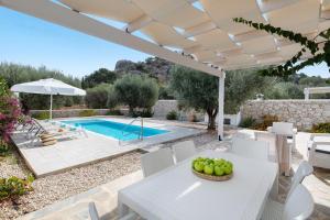 a patio with a table and chairs and a swimming pool at Kalathos Dream Villas in Kalathos