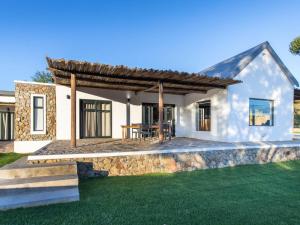 a white house with a stone wall and grass at Ludicks Farm in Montagu
