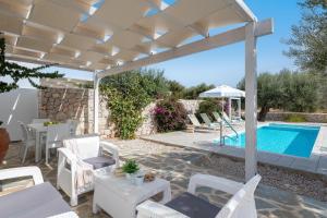 a patio with a white pergola and a swimming pool at Kalathos Dream Villas in Kalathos