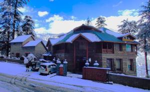 a house with snow on the roof of it at Heritage Satikva Resorts in Manāli