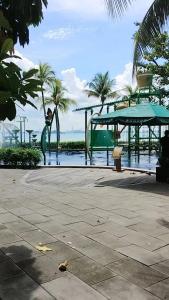 a park with a playground and water and palm trees at 坐忘城市19 in Gelang Patah