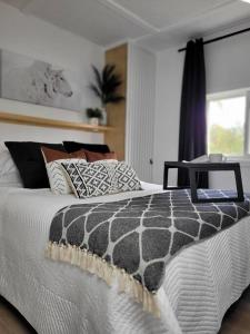 a bed with a black and white comforter and a window at Spot Caché - Waterfront - Water sports included! in Papineauville