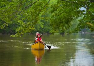 un hombre y una mujer en una canoa en un río en Spot Caché - Waterfront - Water sports included!, en Papineauville
