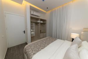 een witte slaapkamer met een bed en een kast bij شقة بغرفتي نوم بتصميم أنيق مع مدخل خاص in Riyad