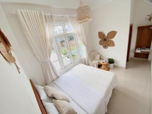 1 dormitorio con cama blanca y ventana en Lantana Homestay en Da Lat