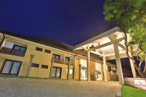 a large building with a porch and a tree at Rajarata Hotel Anuradhapura in Anuradhapura