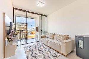 un soggiorno con divano e balcone di Apartamento, Com Piscina - 350m da Praia de Bombas - 2 Suítes, 6 Pessoas a Bombinhas