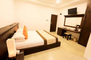 a bedroom with a bed and a desk with a mirror at Rajarata Hotel Anuradhapura in Anuradhapura