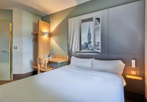 a large white bed in a room with a window at B&B HOTEL Caen Mémorial in Caen