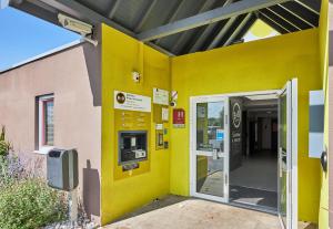 an entrance to a building with a yellow wall at B&B HOTEL Caen M&eacute;morial in Caen