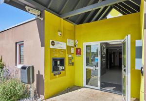 een ingang naar een gebouw met een gele muur bij B&B HOTEL Caen Mémorial in Caen