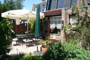 eine Terrasse mit einem Tisch und einem Sonnenschirm in der Unterkunft Heggerank 23B* in Nieuwvliet