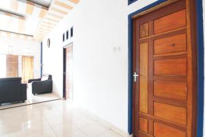 um quarto com uma porta de madeira e um quarto com cadeiras em SPOT ON 93378 Lona Guest House Syariah em Parit