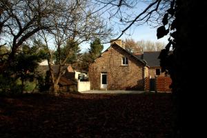une grande maison en briques avec un garage dans une cour dans l'établissement Gîte du Chat noir (Brocéliande), à Campénéac