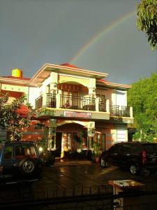 un arco iris sobre un edificio con un coche aparcado delante en Hotel Edelweis 2 Bajawa, en Bajawa