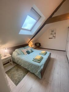 1 dormitorio en el ático con 1 cama y tragaluz en Gîte Le Chêne doré, en La Boussac