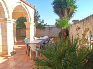 贝瓦尼亚圣彼得Villa Vacanze Perla del Salento - Casa Vacanze San Pietro in Bevagna - SALENTO - Puglia - ITALY的一个带桌椅和棕榈树的庭院