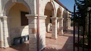 贝瓦尼亚圣彼得Villa Vacanze Perla del Salento - Casa Vacanze San Pietro in Bevagna - SALENTO - Puglia - ITALY的人行道上设有拱门和长凳的建筑 更多12张照片