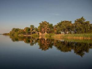 卡蒂馬穆利洛的住宿－Zambezi King Fisher Lodge，海岸上一片树木的水域